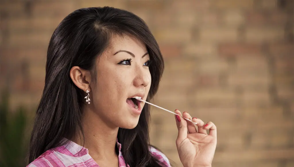 Photo of a woman swabbing her cheek for registry with Be The Match.