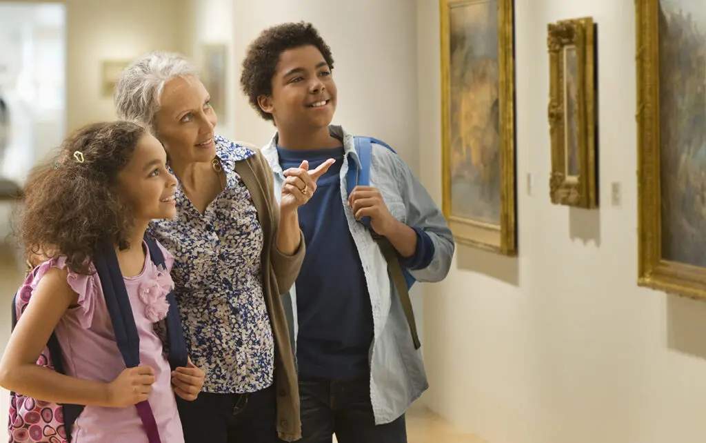 A museum member shows their grandchildren a painting.