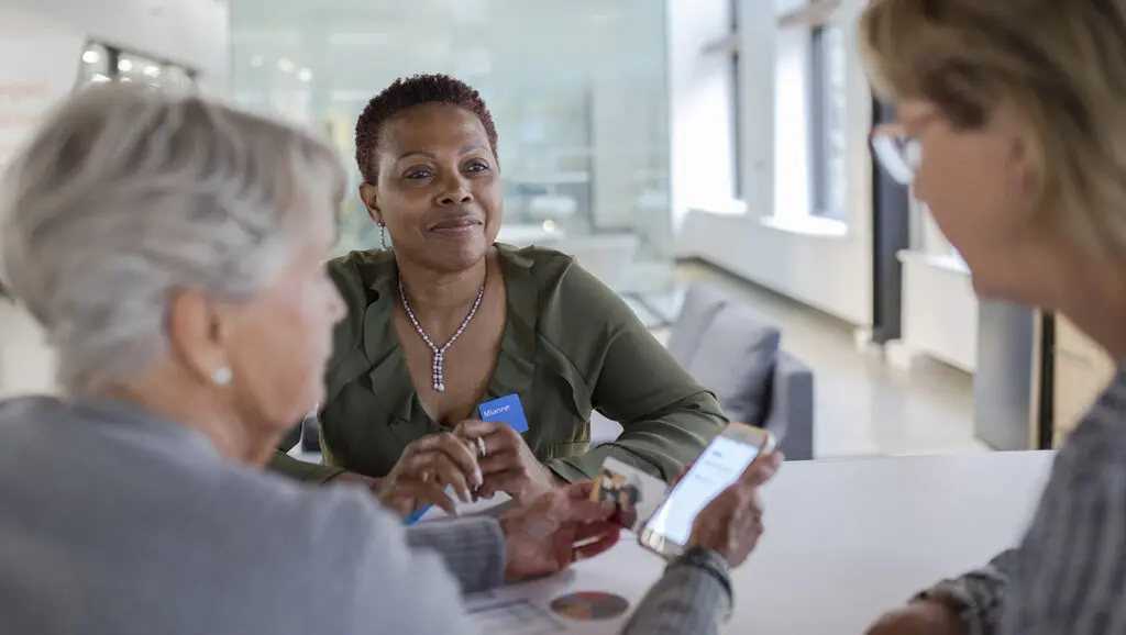 A development team member sits at a table with two donors to discuss planned giving.