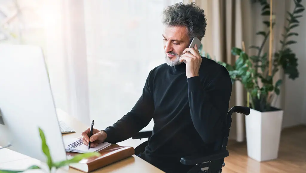 A college or university fundraiser takes notes at their desk while on a call to try and acquire a new donor.