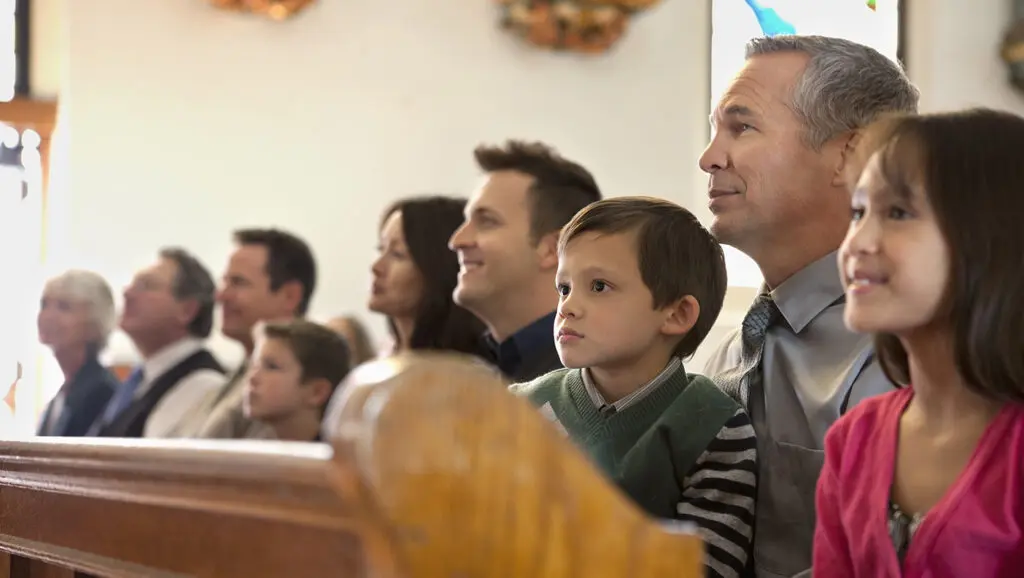 A picture of engaged Church members sitting in the pews of a Catholic Church that put in place an increased offertory program.