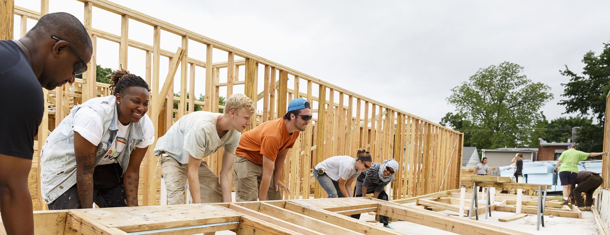 Four volunteers hold the wooden beam of a house.