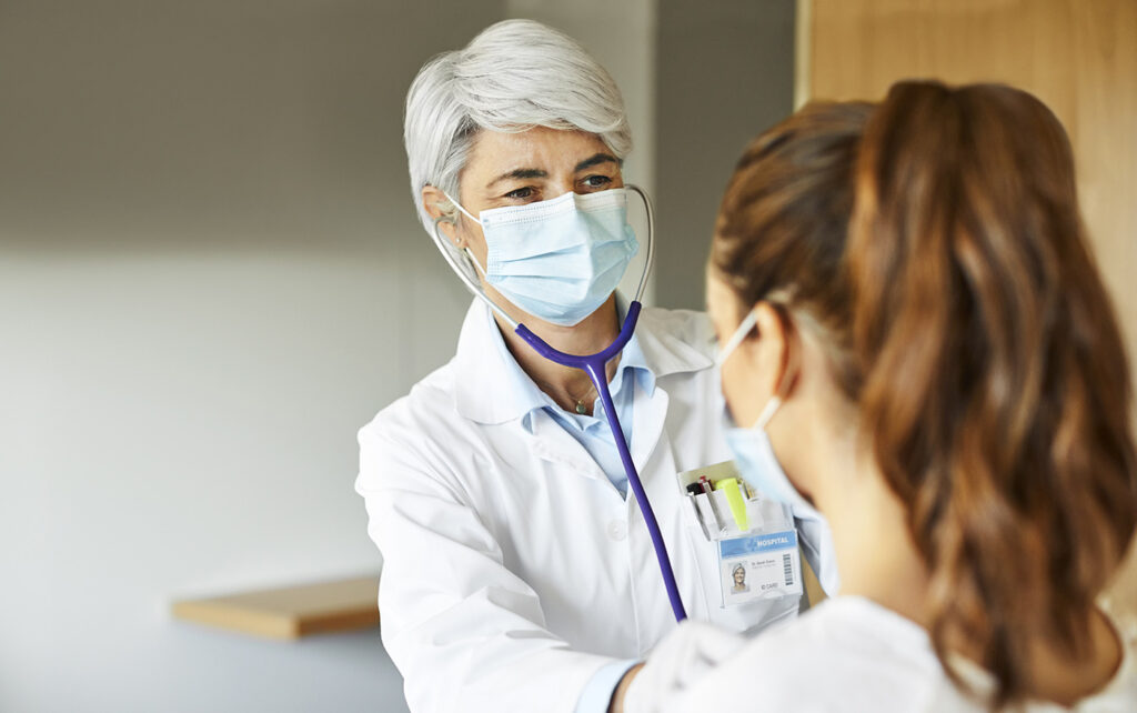 Doctor examining female through stethoscope