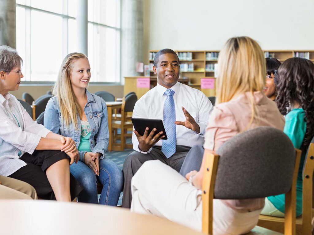 Man leading discussion group of adults and teens