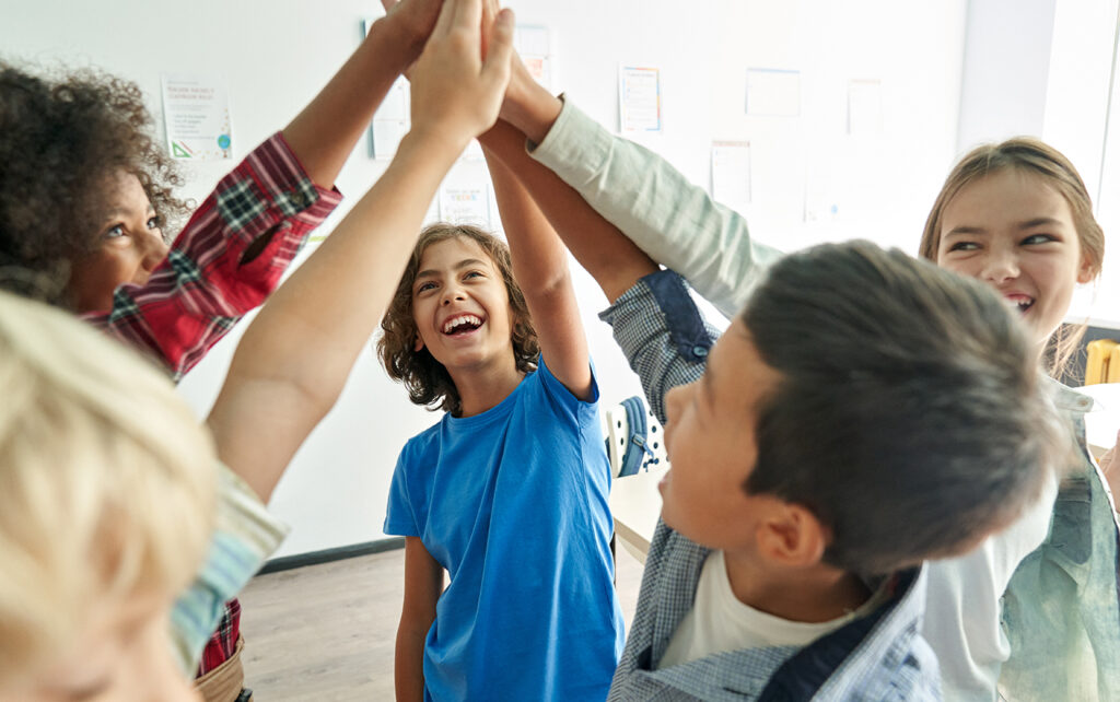 A diverse group of elementary-aged kids high-five.