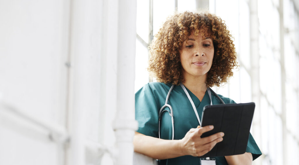 Woman in green scrubs looking at iPad