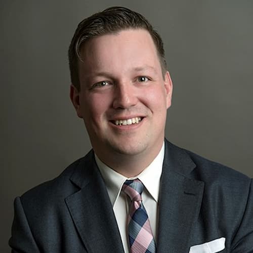 Headshot of a smiling man in a suit.