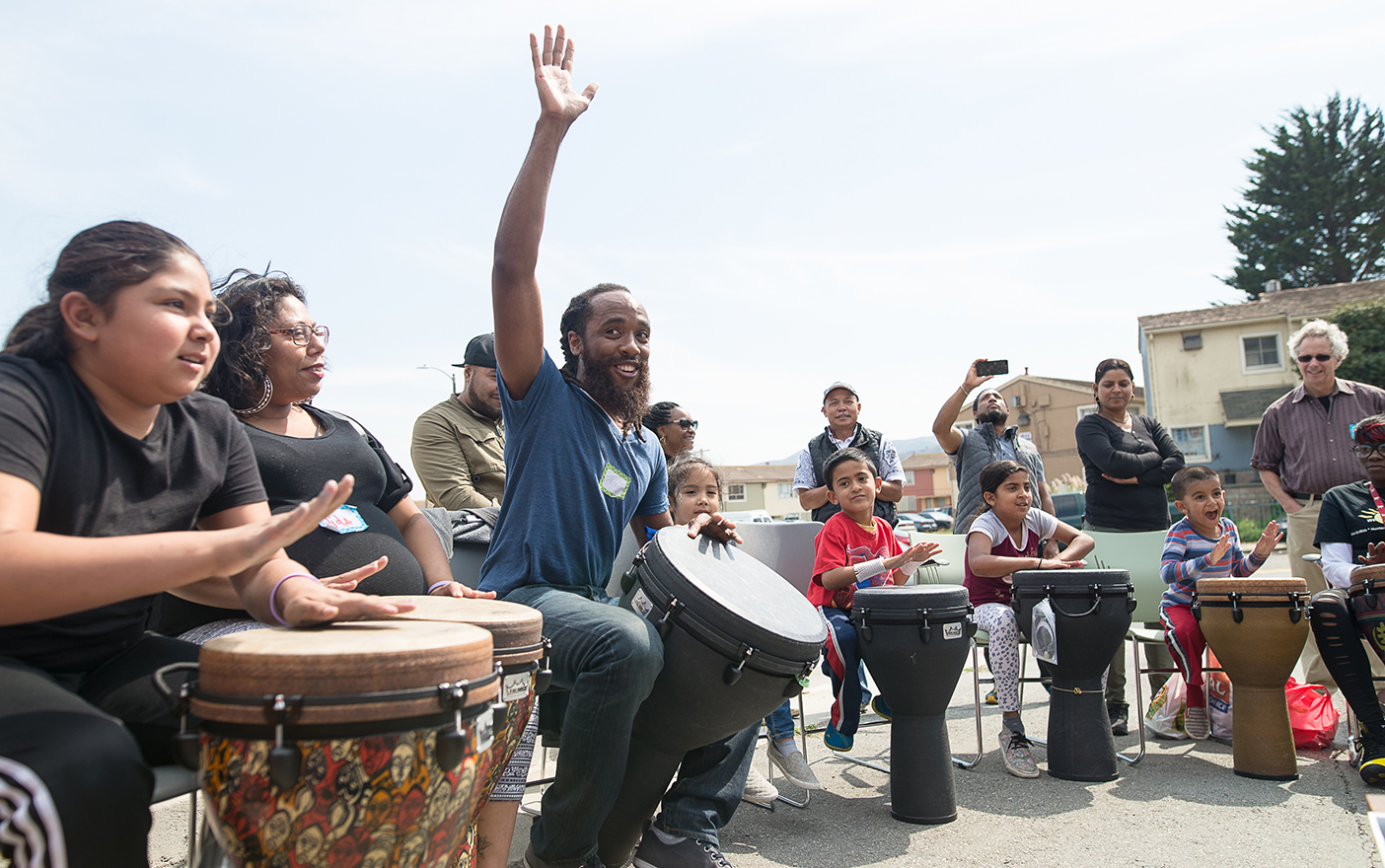 A picture of members of the San Francisco community playing djembe drums outside.