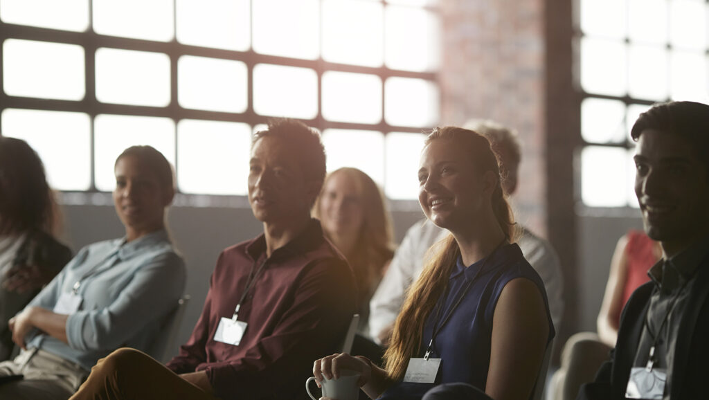 Fundraising professionals tune into a presentation on the philanthropy and economic outlook while sitting in a sunlit room.