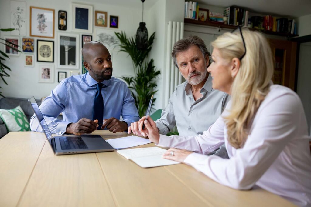 A picture of a financial advisor discussing the tax benefits of charitable giving in the UK with two British donors.