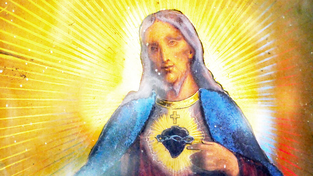 A picture of an old backlit stained glass window depicting Jesus Christ with the Sacred Heart, illustrating the principles of successful Catholic fundraising.