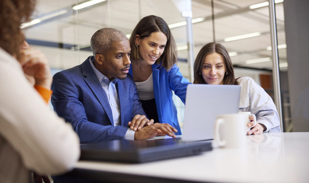 A picture of an office meeting around a laptop.