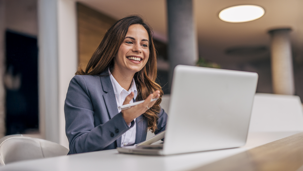 A picture of a nonprofit professional watching the Perspectives on Philanthropy | Giving USA 2025 webinar on their laptop while holding a pen in one hand.