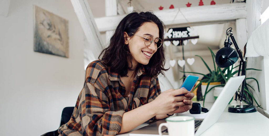 A picture of a young donor on multiple devices to demonstrate an effective nonprofit communications strategy.