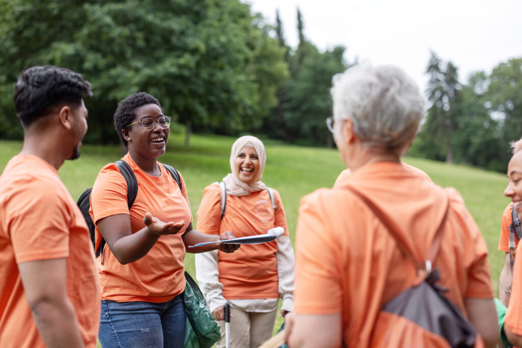 Group of volunteers in orange t-shirts standing in a field